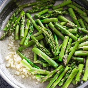 Top view of garlic and asparagus in a stainless steel pot