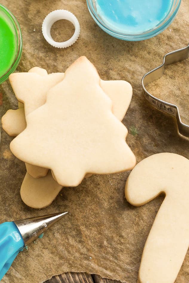 Top view of a stack of Keto Sugar Cookies next to bowls of colorful icing