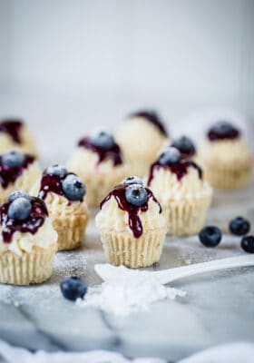 Side view of low carb keto blueberry lemon cheesecakes on a white plate