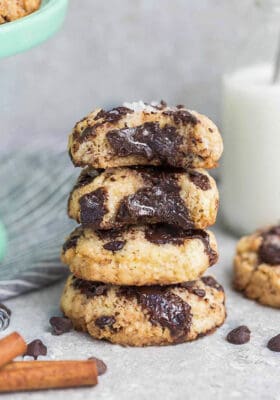 Side view of 4 partially eaten Low Carb Keto Chocolate Chip Cookies stacked with a milk jug behind