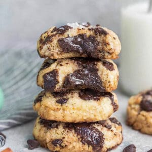 Side view of 4 partially eaten Low Carb Keto Chocolate Chip Cookies stacked with a milk jug behind