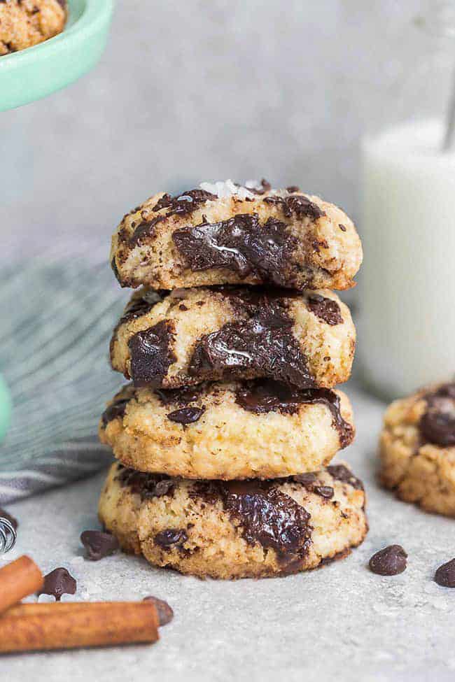 Side view of 4 partially eaten Low Carb Keto Chocolate Chip Cookies stacked with a milk jug behind