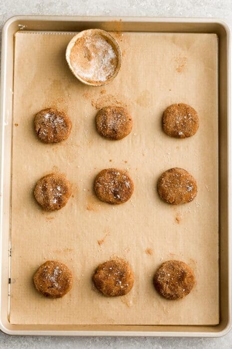 Top view of 9 unbaked low carb molasses cookie dough on parchment paper on a baking sheet