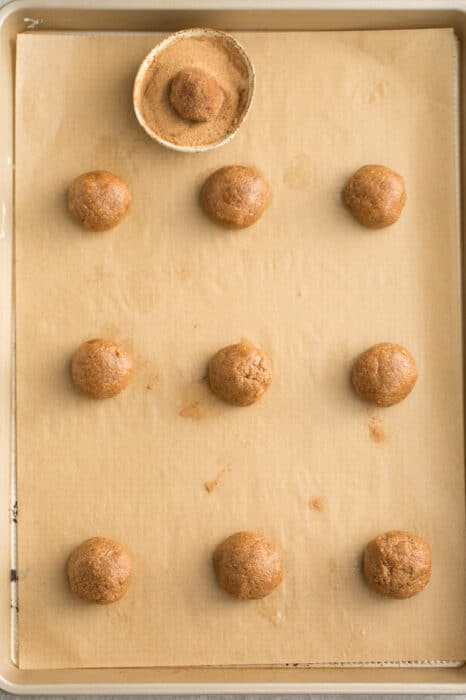 Top view of 9 unbaked low carb gingersnaps cookie dough on parchment paper on a baking sheet