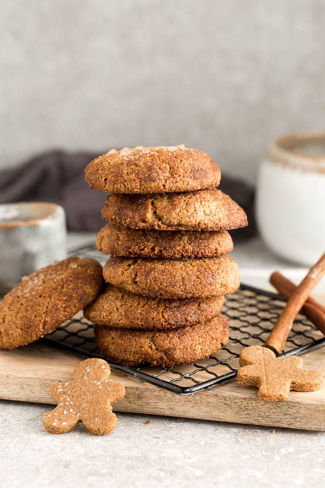 Side view of 7 stacked low carb vegan soft ginger molasses cookies on a wire rack on a grey background