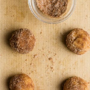 Top view of unbaked low carb snickerdoodle cookie dough in a bowl with cinnamon sugar bowl on a grey background