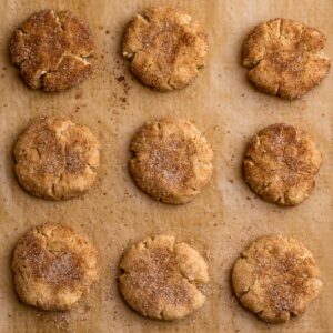 Top view of 9 keto snickerdoodles on parchment paper on a baking sheet