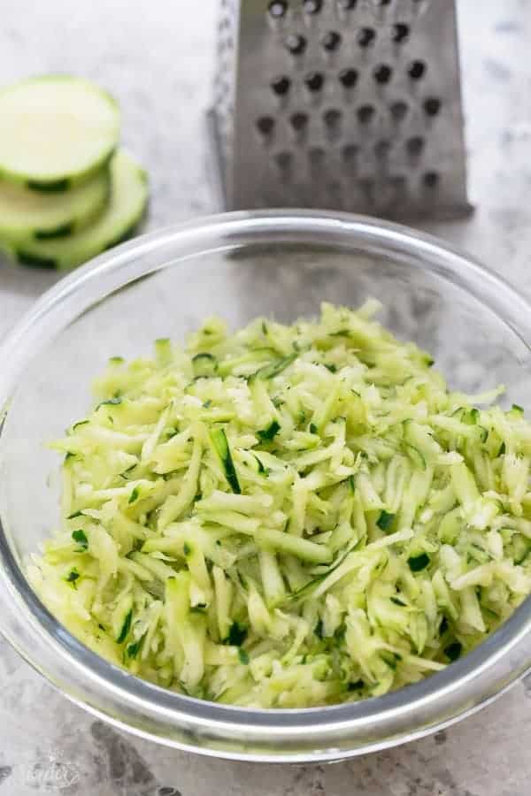 Top view of grated zucchini in clear glass bowl. 
