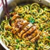 Top close-up view of Low Carb Zucchini Noodles with Chicken in a stainless steel pan on a wodden board with chopsticks