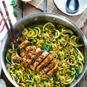 Top view of Low Carb Zucchini Noodles with Chicken in a stainless steel pan on a wodden board with chopsticks