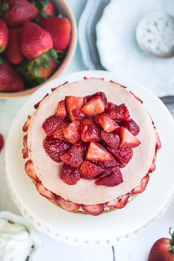 Top view of Low Carb Strawberry Cheesecake topped with fresh strawberries on a white cake pedestal