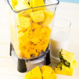 Chopped mango and pineapple in a blender to make a mango smoothie
