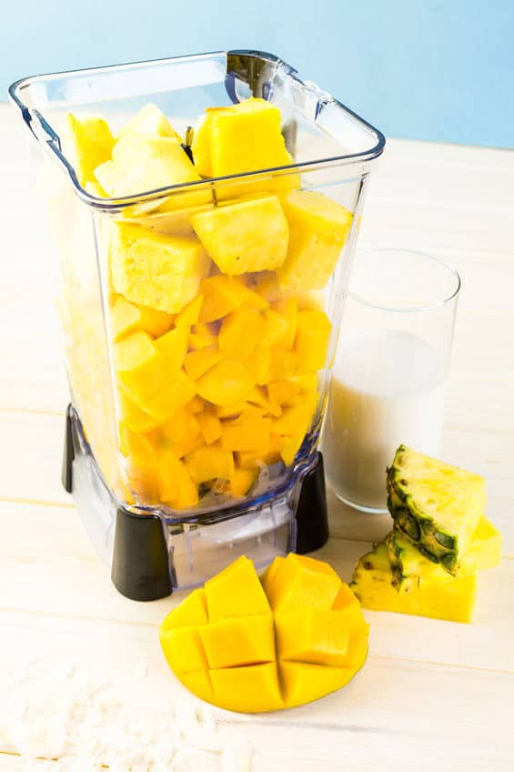 Chopped mango and pineapple in a blender to make a mango smoothie