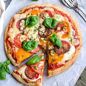 Margherita Pizza - a simple classic recipe that's made with Heirloom tomatoes, mozzarella and fresh basil. Easy and perfect for busy weeknights. Best of all, simple to customize with your favorite toppings