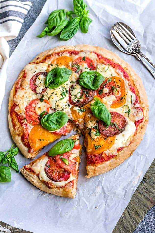 Margherita Pizza - a simple classic recipe that's made with Heirloom tomatoes, mozzarella and fresh basil. Easy and perfect for busy weeknights. Best of all, simple to customize with your favorite toppings