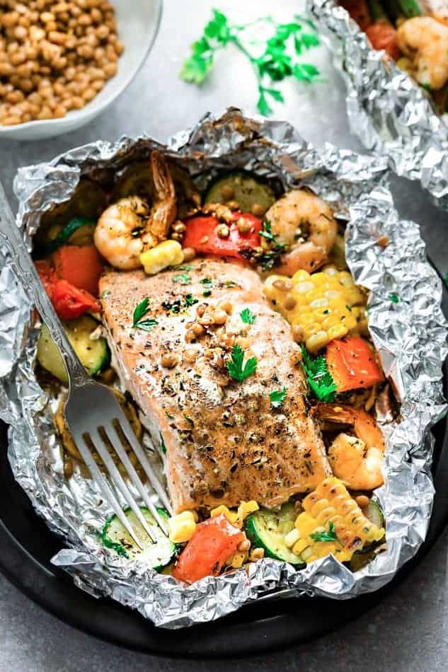 Top view of a foil packet with Mediterranean salmon surrounded by shrimp and vegetables