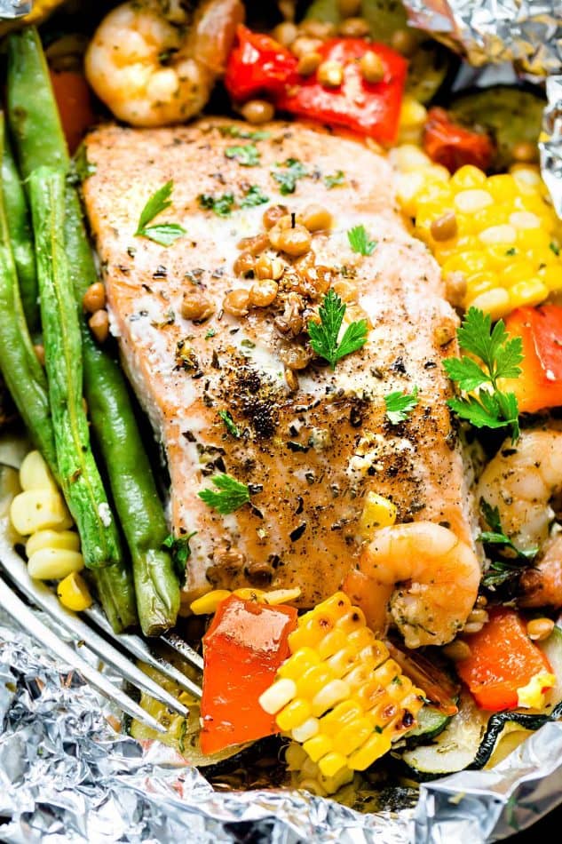 Close-up of a foil packet with Mediterranean Salmon surrounded by shrimp and vegetables