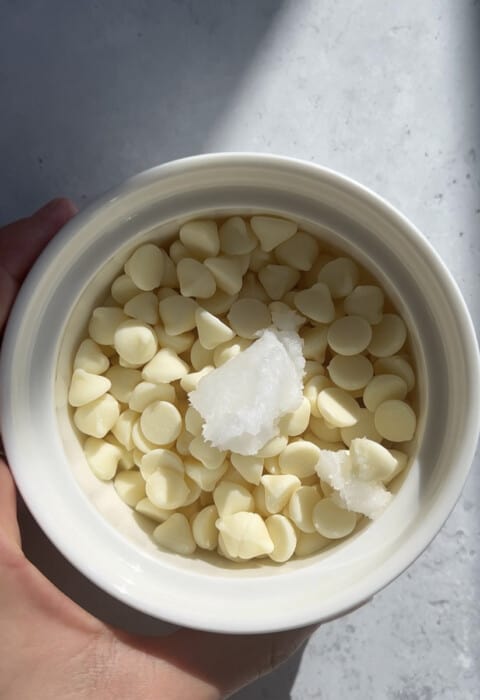 White chocolate chips and coconut oil in a white ramekin