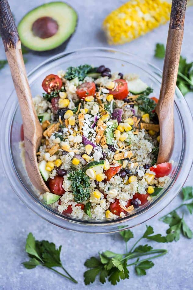 Top view of Mexican Quinoa Salad in a mixing bowl with two wooden spoons