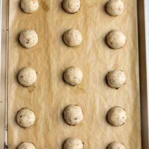 Top view of 15 baked uncoated butterballs on a parchment paper lined baking sheet