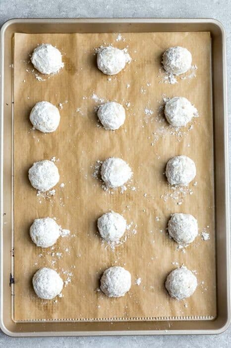Top view of 15 baked coated butterballs on a parchment paper lined baking sheet