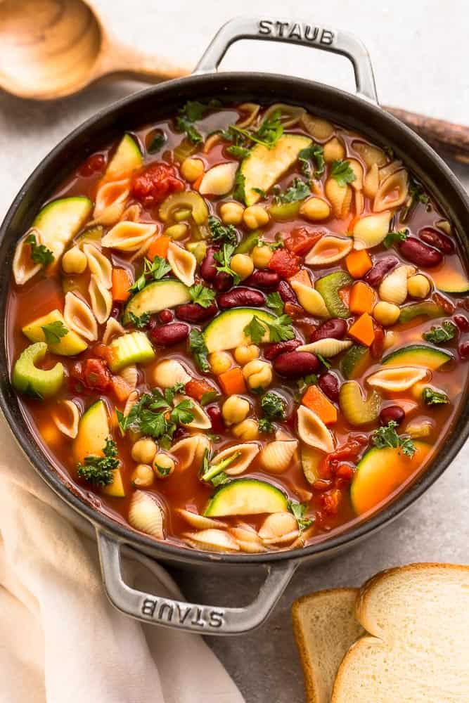 Top view of Instant Pot Homemade Minestrone Soup in a large cast iron pot with two slices of bread and a ladle behind