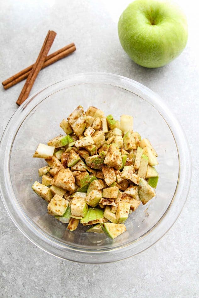 Top view of diced apples in glass bowl with cinnamon.