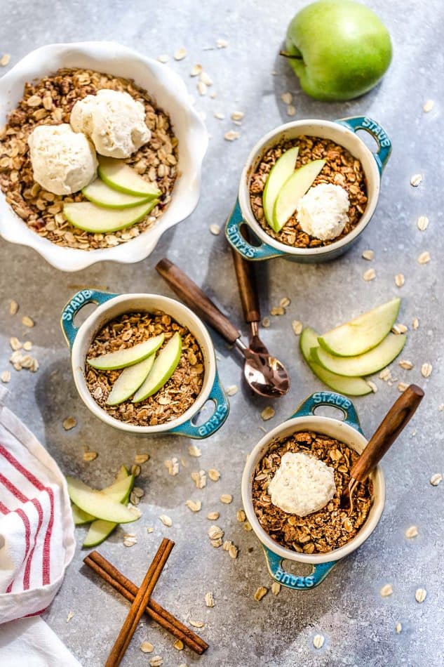 Top view of four bowls of gluten free apple crisp with fresh apples.