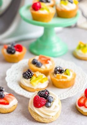 Mini Fruit Pizza desserts scattered on and around a dessert plate