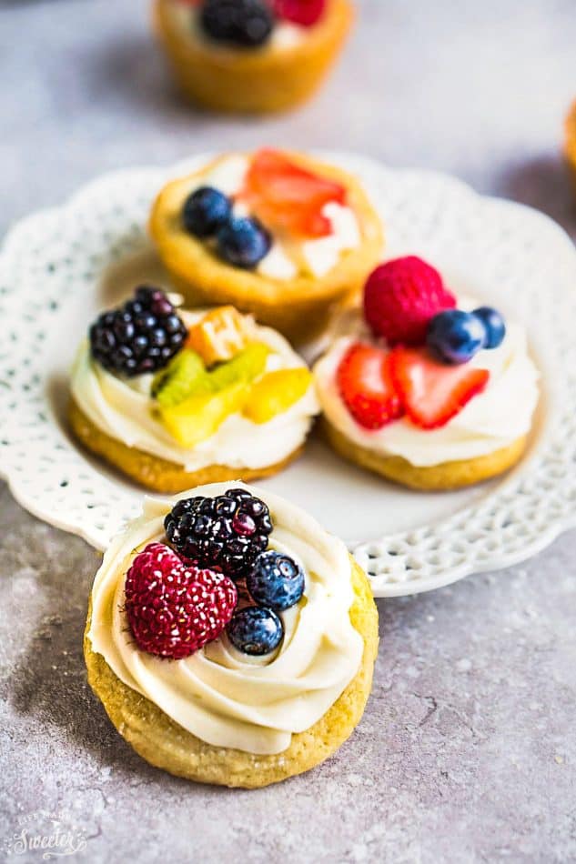 Mini Fruit Pizza - a classic dessert made using homemade soft sugar cookies topped with fresh fruit. Perfect for spring or summer barbecues, potlucks, showers, and parties. Best of all, no dough chilling required and easy to customize! Use a mix of fresh strawberries, blueberries, blackberries, raspberries, kiwi, mandarin oranges or pineapples!