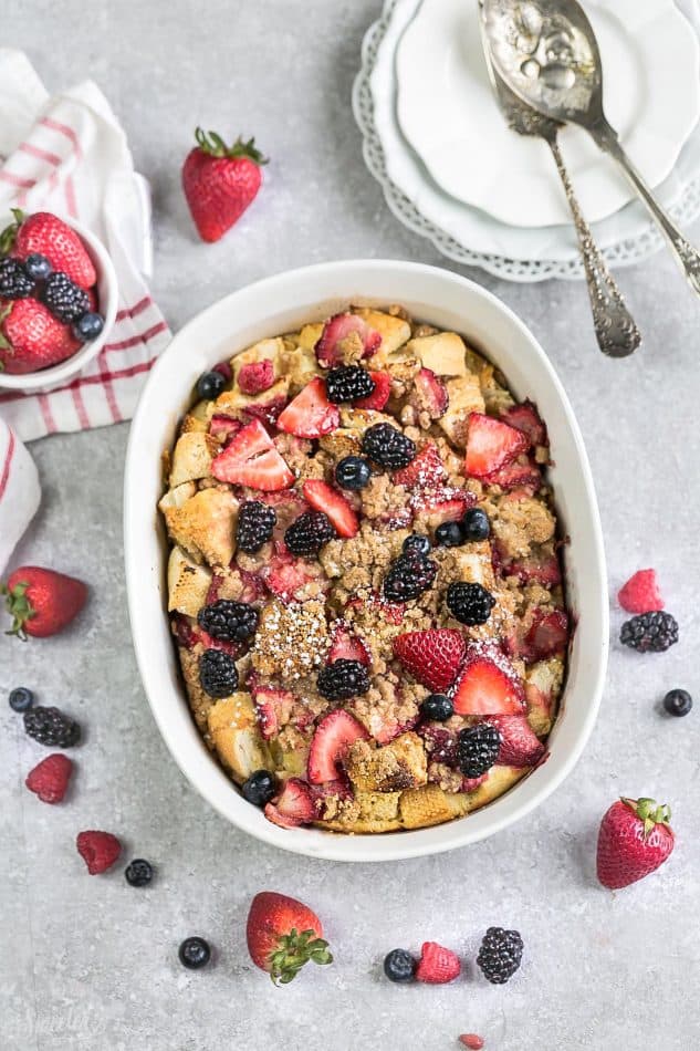 An overhead shot of a baked mixed berry French Toast Casserole in a white oval casserole dish