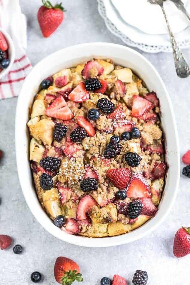 An overhead shot of a baked mixed berry French Toast Casserole in a white oval casserole dish