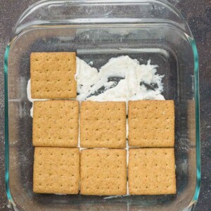 Layers of gluten-free graham crackers in a square casserole dish with cream underneath