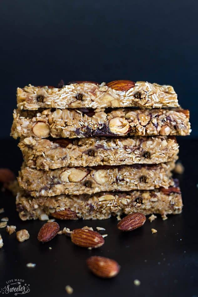 Five granola bars stacked on top of each other, surrounded by whole almonds