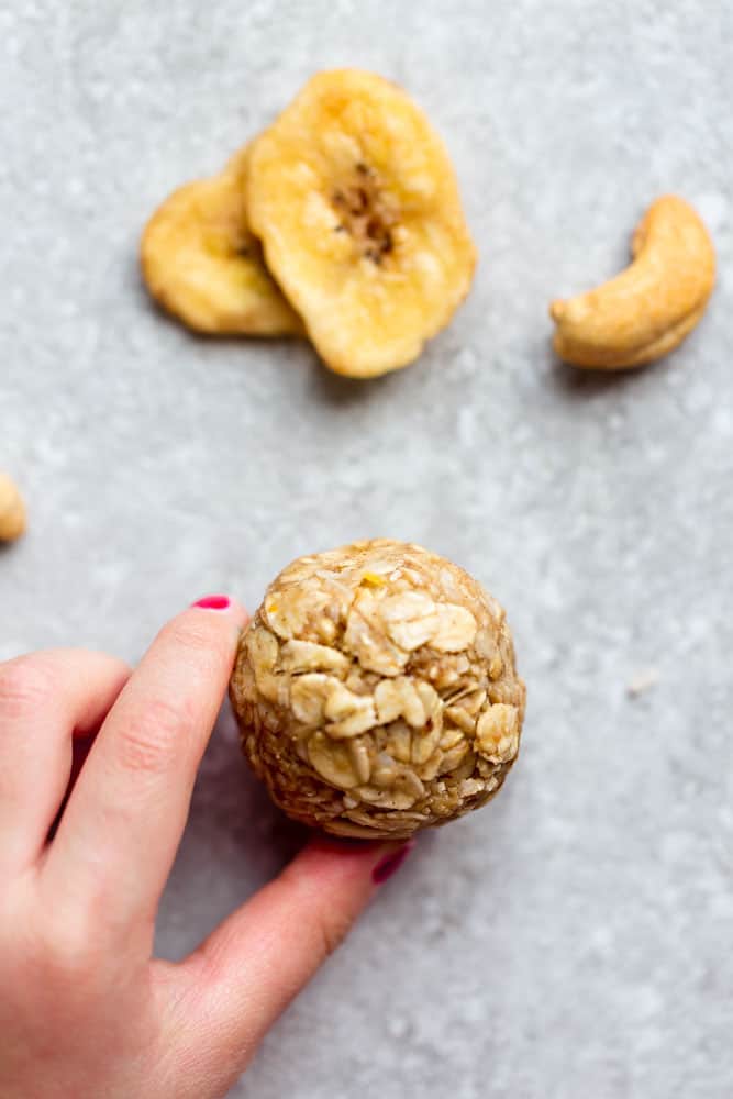 Close up view of Banana Nut Energy Bites with a hand holding it
