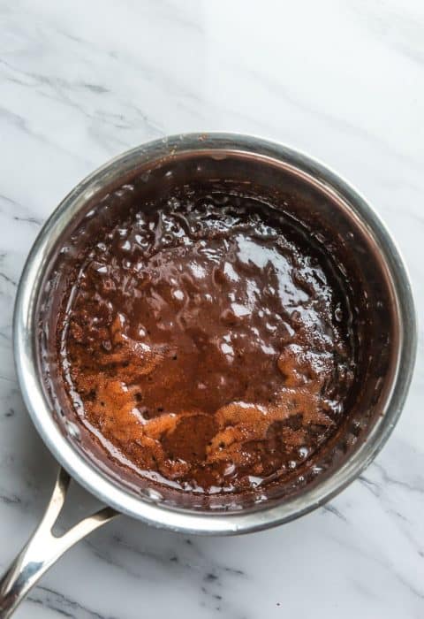 Top view of melted chocolate to make Low Carb No Bake Cookies in a stainless steel pot on a white background