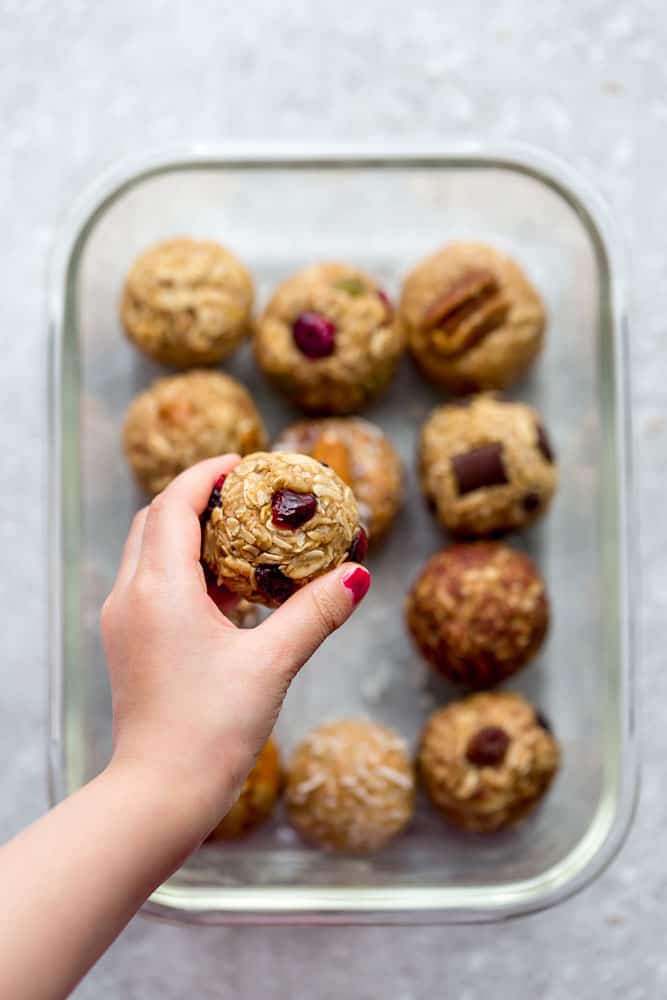 A kid holding a no bake energy ball made with dried fruit and nuts