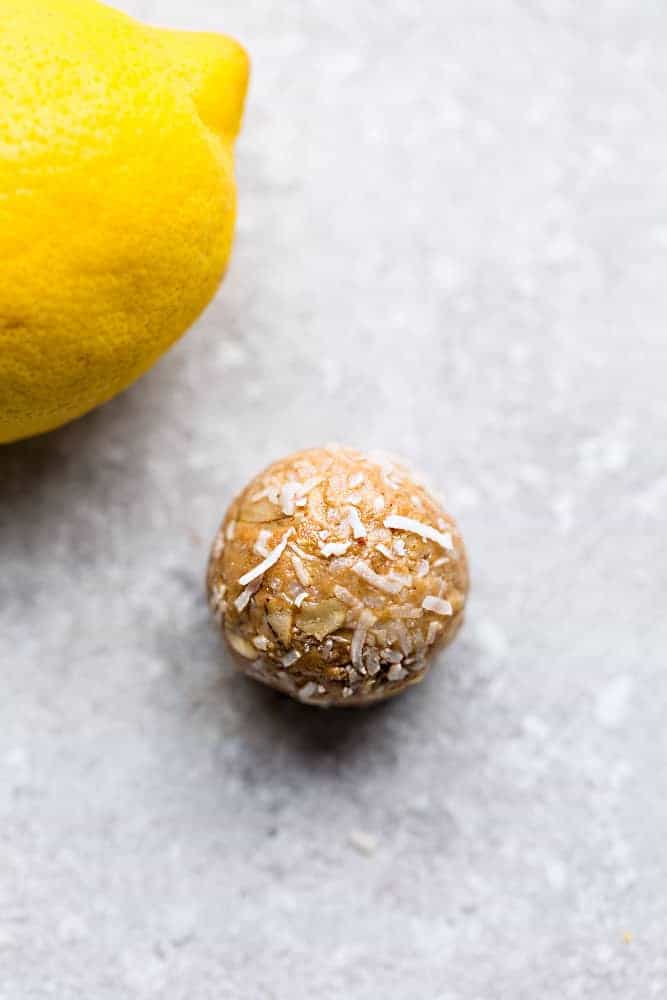 A whole lemon sits next to a no bake lemon energy ball