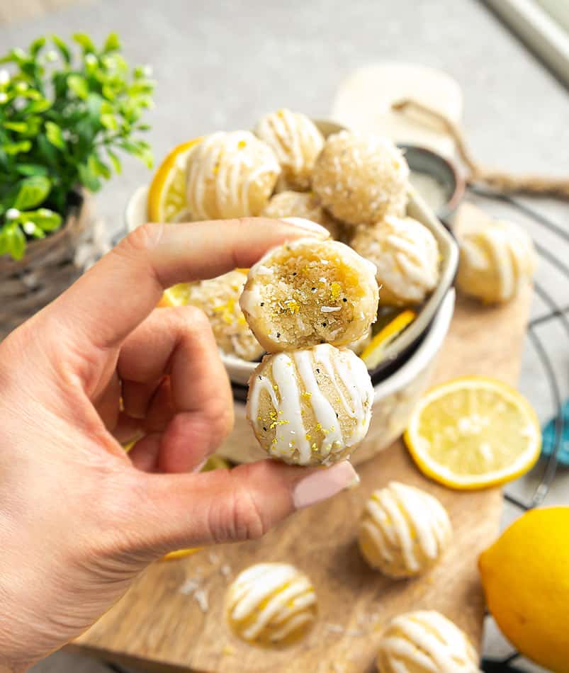 Side view of a Hand holding two lemon protein balls