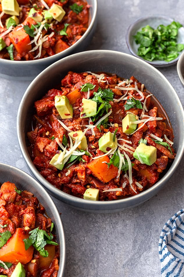 A few bowls of Vegan chili topped with cilantro and diced avocado