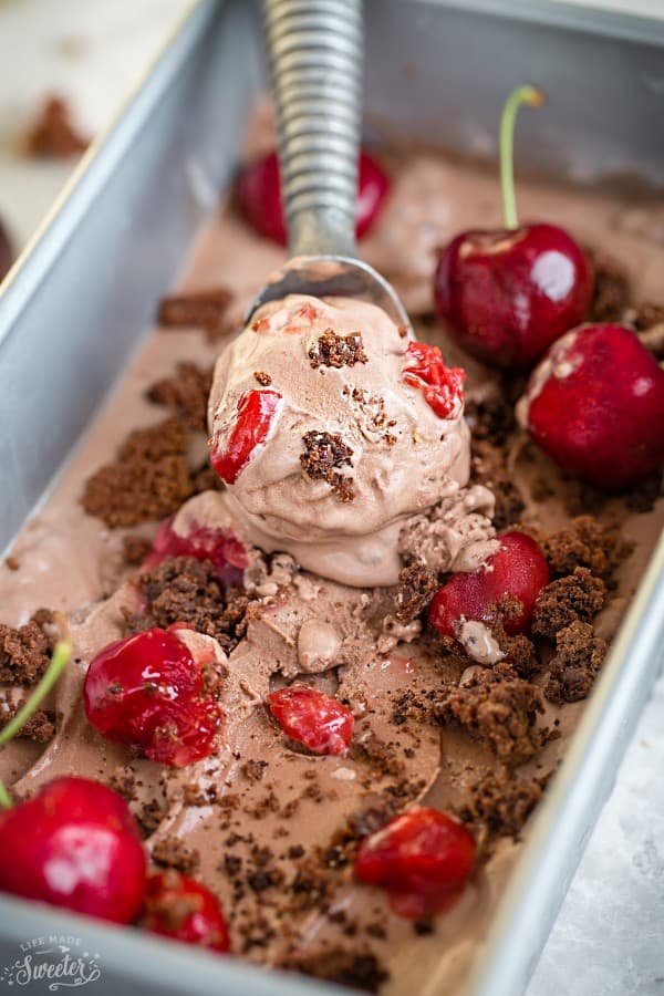 Close-up view of an ice cream scoop dipping into a pan of No Churn Black Forest Ice Cream