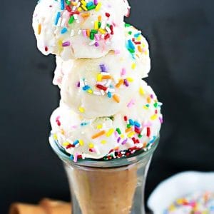 Several scoops of No Churn Cake Batter Funfetti ice cream in a sugar cone in a glass