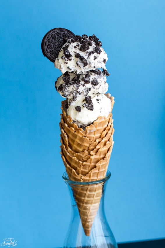 No Churn Cookies and Cream Oreo Ice cream scooped into a stack of waffle cones with an oreo on top