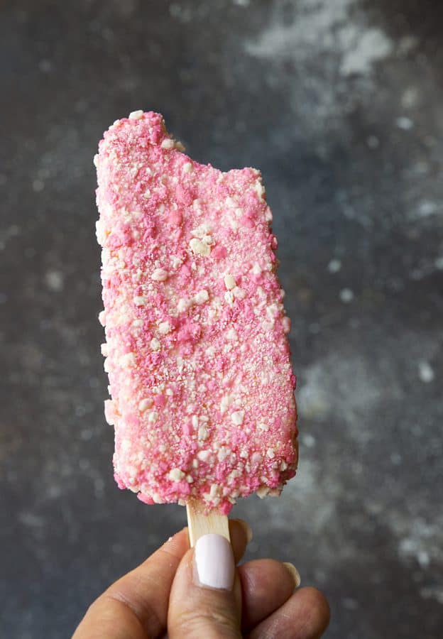 A Strawberry Shortcake Ice Cream Bars on a stick with a bite missing