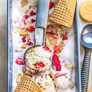 Top view of No Churn Strawberry Shortcake Ice Cream in a pan with cones and a scoop