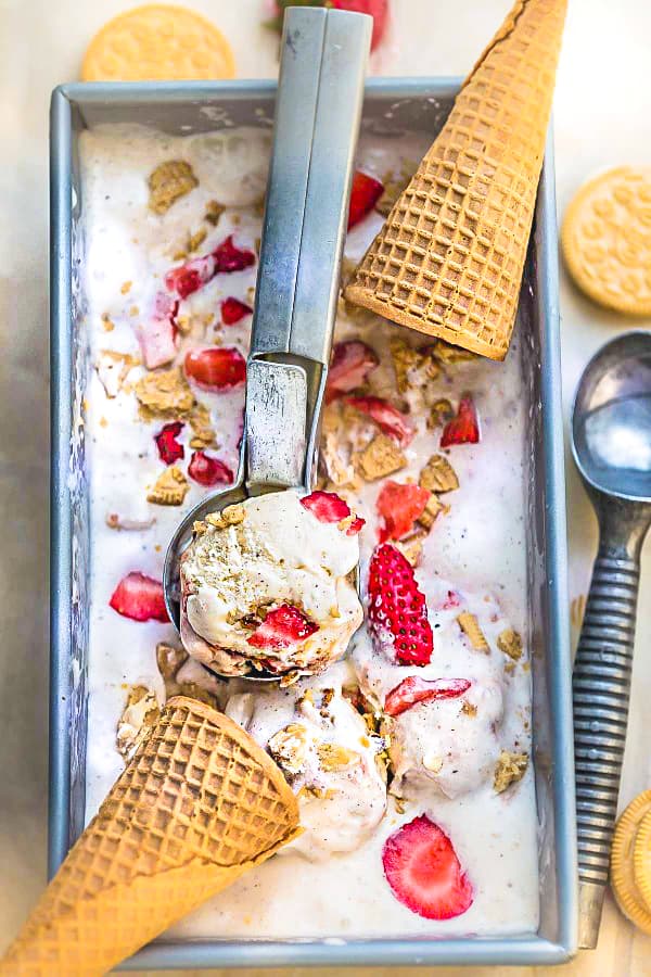 Overhead view of no churn strawberry shortcake ice cream with fresh strawberries and silver scooper.