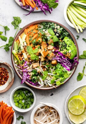 Overhead view of a vegan power bowl surrounded by bowls of individual ingredients
