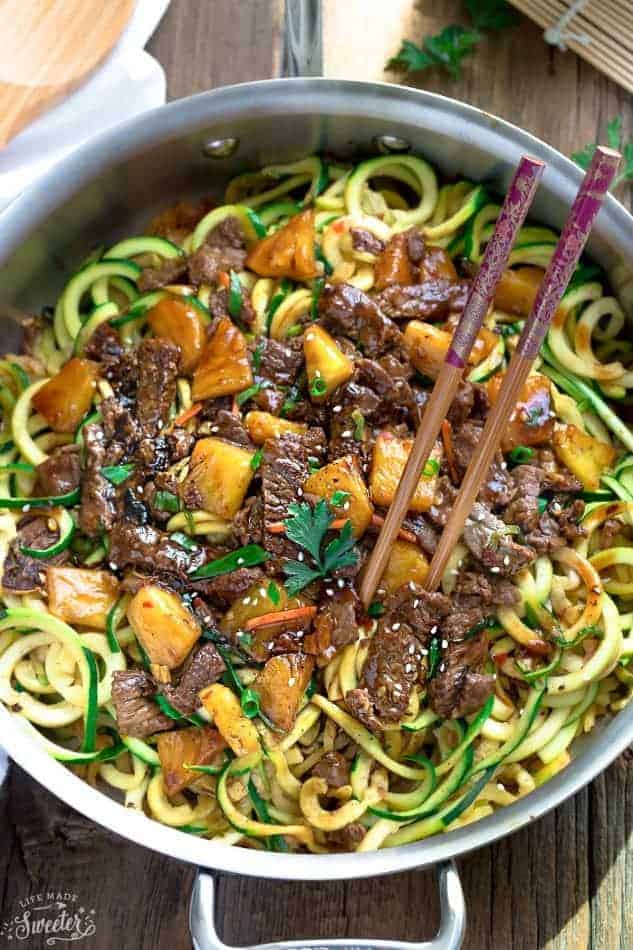 Close-up view of Top view of Mongolian Beef stir fried with zucchini noodles in a stainless steel pan with chopsticks