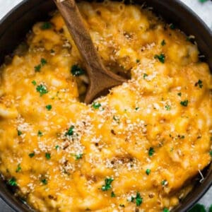 Pinterest image of one pot macaroni and cheese with fresh parsley and a wooden spon on white surface.