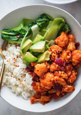 Orange Cauliflower with bok choy and cauliflower rice in a white bowl